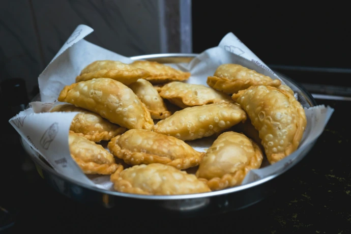 A metal bowl filled with fried food on top of a stove